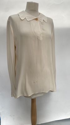 beige shirt on a mannequin stand in front of a white backdrop