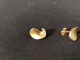 a pair of gold plated earrings on a black surface
