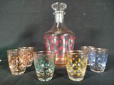 five glasses and a decanter sitting on a table