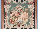un gros plan sur une broderie représentant des fleurs, dans un cadre en bois