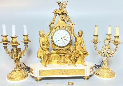 une horloge en or posée sur une table, à côté de bougies