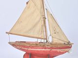 wooden model of a sailboat with a red hull and white sails