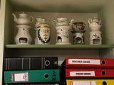 a shelf that has many different types of binders and mugs on it