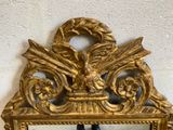 a gold mirror with a bird on it on the wall