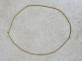 a close up of a gold necklace on a white surface