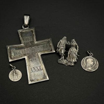 une croix en argent et une médaille sur un fond noir
