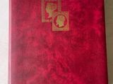 quelqu'un tient un livre rouge orné d'un cachet doré