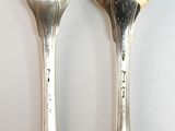 two silver spoons and a fork on a table