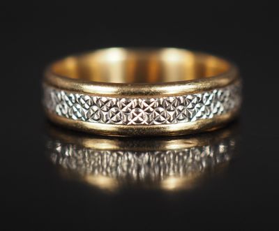 un gros plan d'une bague en or et en argent posée sur une surface noire