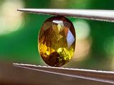 un gros plan d'un diamant jaune tenu par une pince