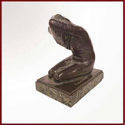 une statue en bronze représentant une femme assise sur un bloc de marbre