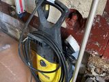 a yellow and black power washer sitting on the ground next to a brick wall