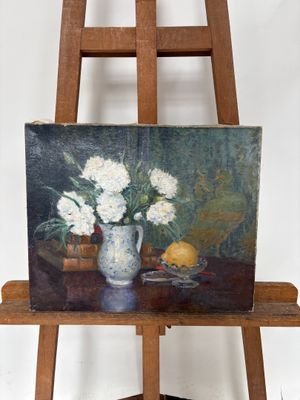 une photo d'un tableau posé sur un chevalet, avec un vase de fleurs