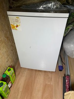 un petit réfrigérateur blanc dans le coin d'une pièce