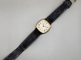 gros plan d'une montre sur une surface blanche avec un bracelet noir
