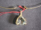 a necklace with a green stone on a red string