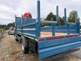 a blue flatbed truck that is parked on the side of the road