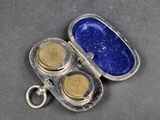 un étui en argent avec deux boutons en or à l'intérieur