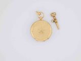 a close up of a gold pocket watch with a key
