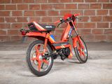 a red motorcycle parked in front of a brick wall