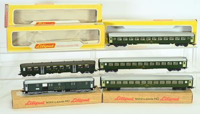 Quatre trains miniatures sont exposés dans une vitrine posée sur une surface blanche.