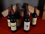 several bottles of wine are lined up on a red table cloth