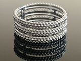 a close up of a stack of silver bracelets on a table