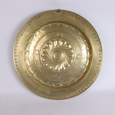 une assiette en or ornée d'un motif sur un fond blanc