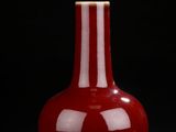 red vase sitting on a black surface with a black background