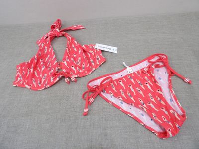 pair of red bikinis on a bed with a tag on it