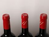 three bottles of red wine are lined up on a table