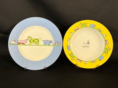 two plates with animals painted on them sitting on a black surface