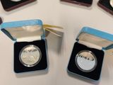 four silver coins are in a blue box on a white table