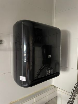 un distributeur de savon noir fixé au mur dans une salle de bains