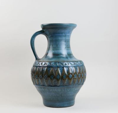 un vase bleu muni d'une anse, sur fond blanc