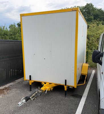 un camion blanc attelé à une remorque jaune dans un parking
