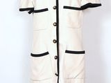a white dress with black trims and buttons on a mannequin mannequin