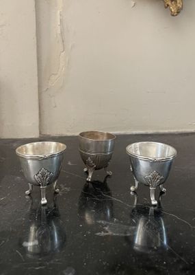 trois tasses en argent posées sur un plan de travail noir
