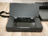 a black printer sitting on a wooden floor next to a laptop