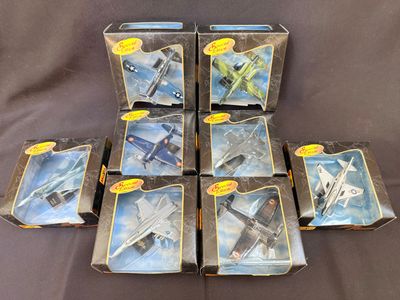 six jouets représentant des avions de chasse, présentés dans leurs boîtes, sur fond noir