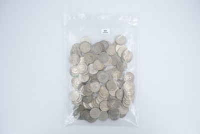 un sac rempli de pièces d'argent posé sur une surface blanche