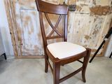 une chaise en bois avec une assise blanche devant une porte en bois