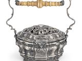 une boîte en argent finement décorée, dotée d'une poignée et de anses, sur fond blanc