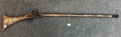 an old gun with a wooden handle on a carpet
