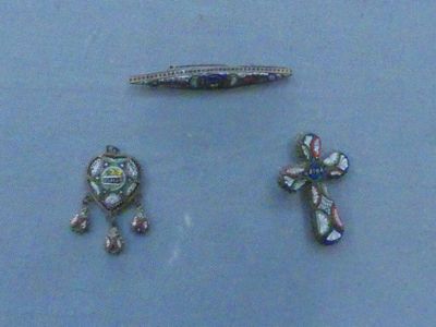 three pieces of jewelry on display on a blue surface