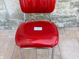 a red chair with a tag on it sitting in front of a stone wall