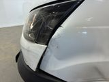 the front end of a white van with a denting headlight