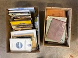 a box full of books sitting on the floor next to a cat