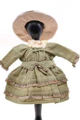 une poupée d'antan vêtue d'une robe verte et d'un chapeau