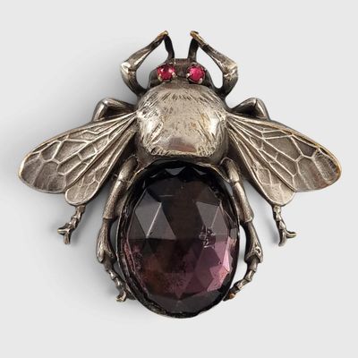 a close up of a bee broochle with a faceted stone